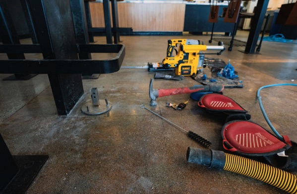 Install kit staged on the slab — rotary hammer, anchors and pads